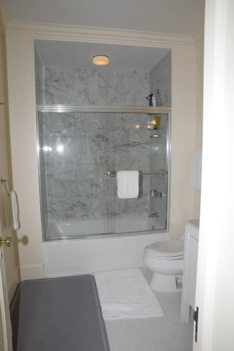 Renovated bathroom with white tiles and glass shower enclosure