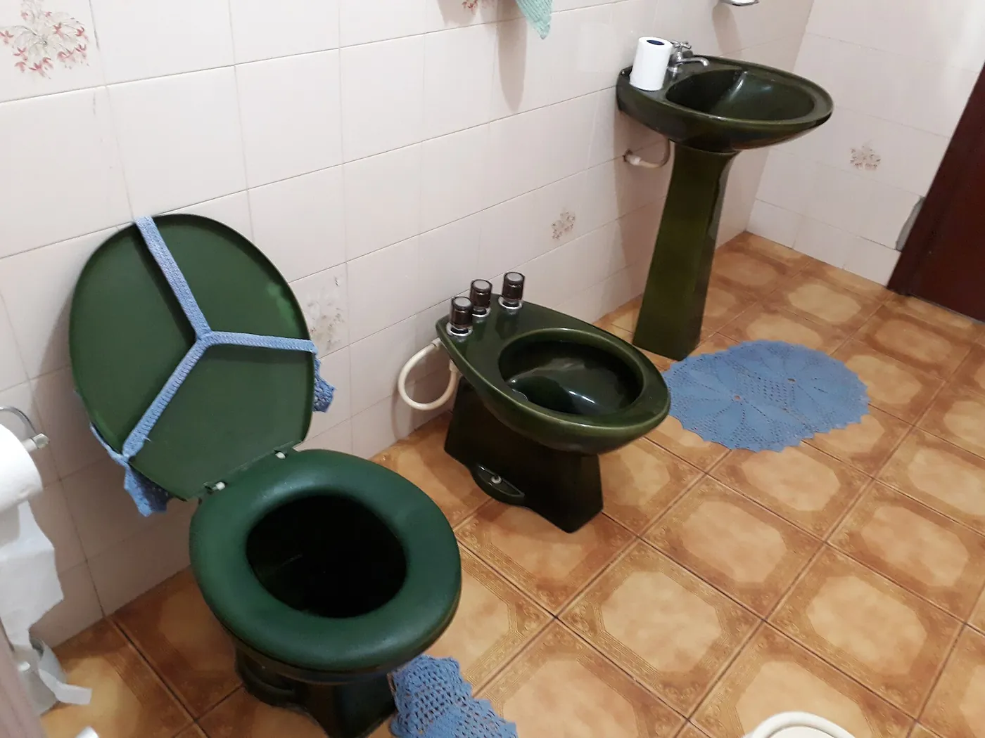 Dated bathroom suite with old coloured sanitary ware and worn tiles