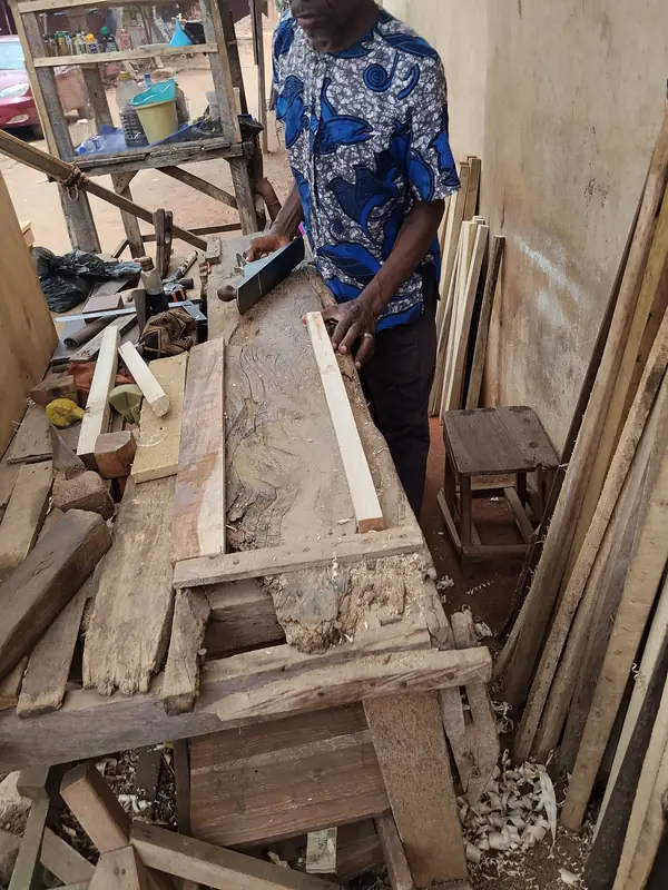 Carpenter planing a length of wood in a workshop