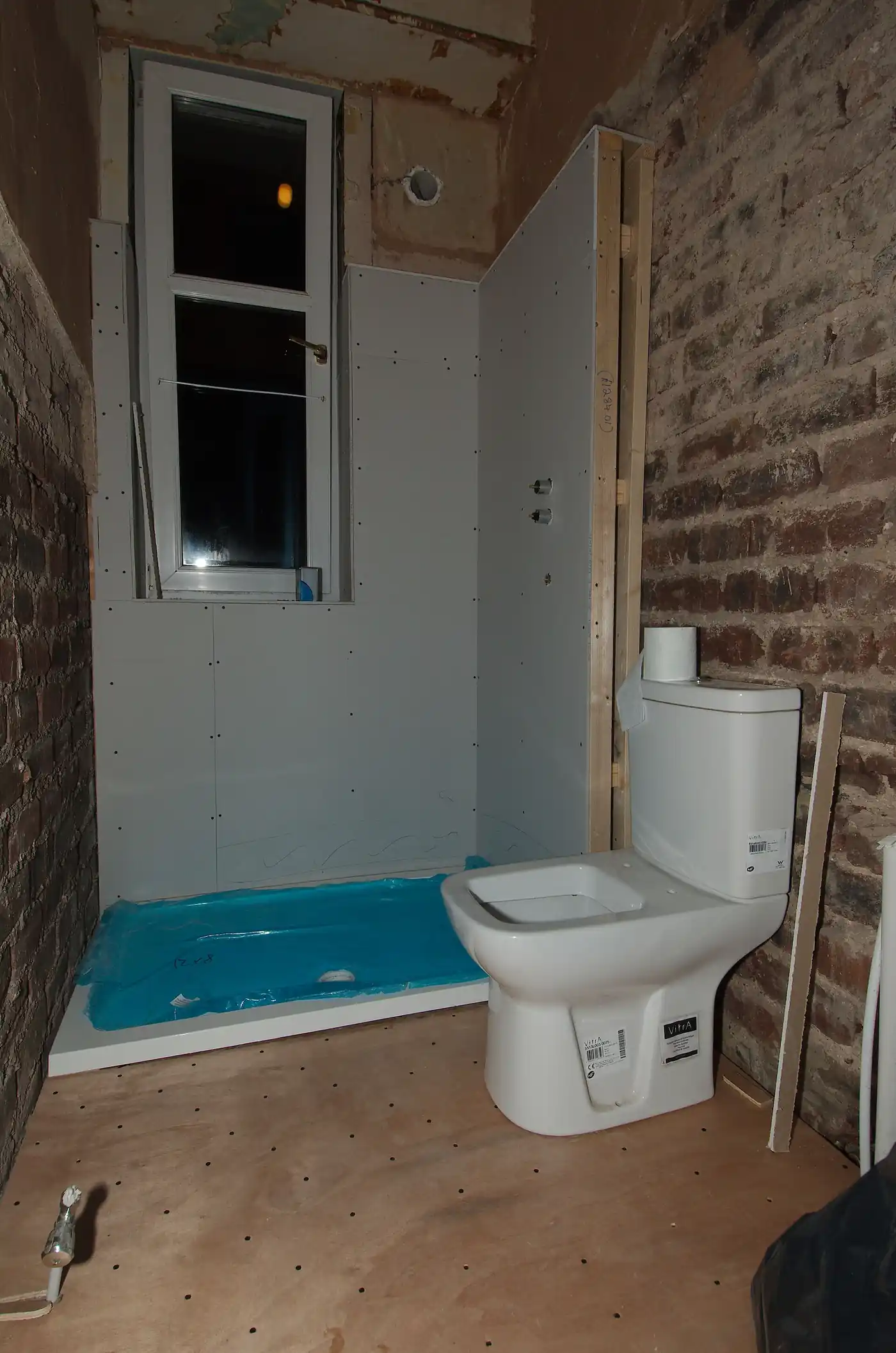 Bathroom mid-renovation with a new WC fitted and the shower area being prepared